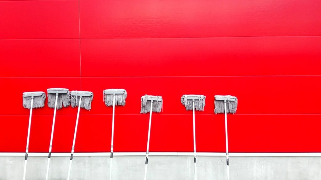 White mops leaning up against a bright red wall